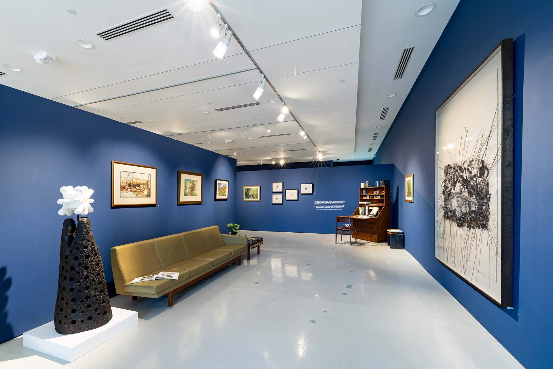 Exhibition artwork Wide view of gallery with artwork on walls and a couch